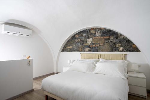 a bedroom with a white bed with a stone wall at The Secret Garden in Como