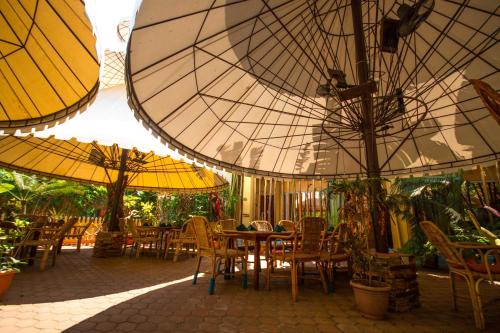 a patio with tables and chairs under umbrellas at Deep Forest Garden Hotel in Puerto Princesa City