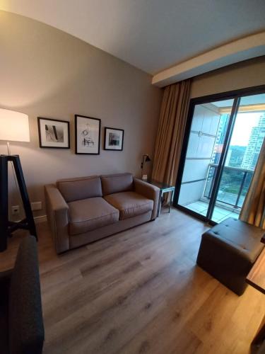 a living room with a couch and a large window at Estanplaza Berrini in Sao Paulo