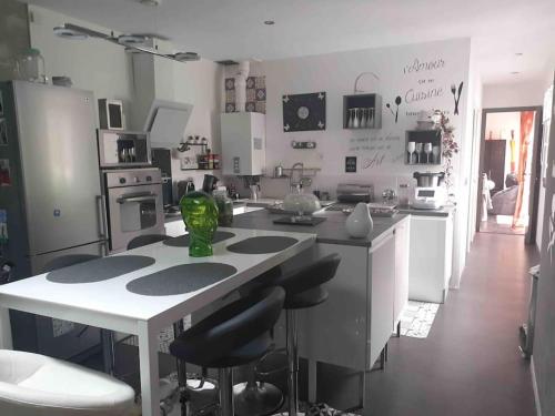 - une cuisine avec une table et des tabourets dans une pièce dans l'établissement Maison de charme au calme à 10mn du centre ville, à La Rochelle