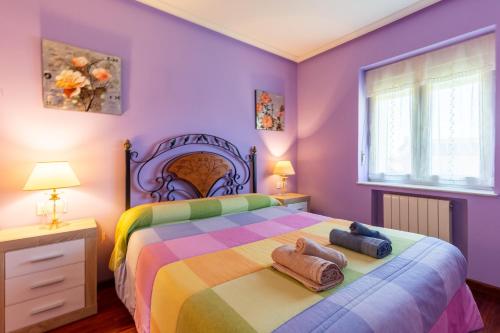 a bedroom with a colorful bed with two towels on it at Casa Rural La Sosiega con jardín privado in Bernueces