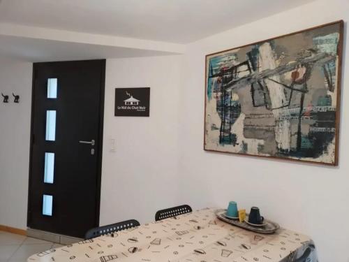 a room with a table and a picture on the wall at Le Nid du Chat Noir - Gîte La Maison Alvéole in Sciez