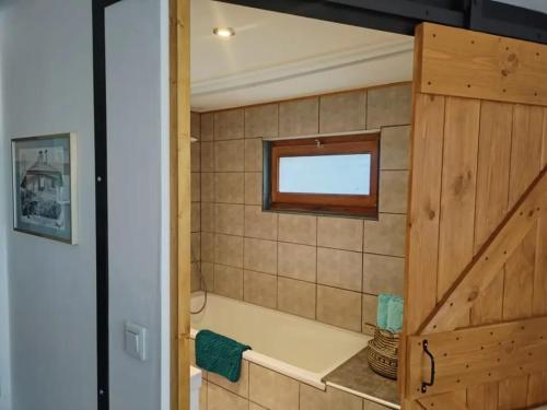 La salle de bains est pourvue d'une baignoire et d'une fenêtre. dans l'établissement Le Nid du Chat Noir - Bed and Books, à Sciez