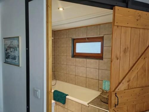 a bathroom with a tub and a window at Le Nid du Chat Noir - Bed and Books in Sciez