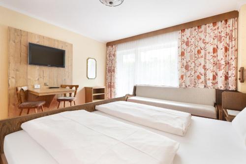 a bedroom with a bed and a table and a television at Pension Glockenstuhl in Finkenberg