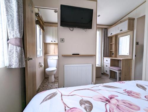 a bedroom with a bed and a tv on the wall at Flamingo Lodge - Mallard Lake in South Cerney