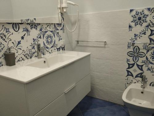 a white bathroom with a sink and a toilet at Hotel La Giara in Zambrone