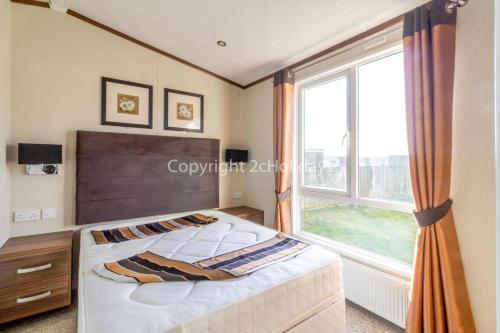 a bedroom with a bed and a large window at Luxury Caravan Nearby The Beautiful Scratby Beach In Norfolk Ref 50001a in Great Yarmouth
