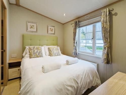 a bedroom with a large white bed and a window at Willow Lodge in South Cerney