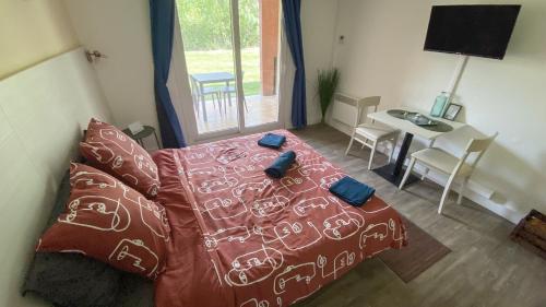 a bedroom with a bed and a table and a window at Joli studio Camargue Lou Rouge Arles in Arles