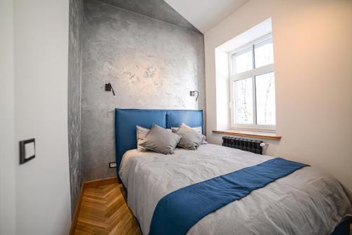 a bedroom with a blue bed and a window at Homly S22 in Rīga