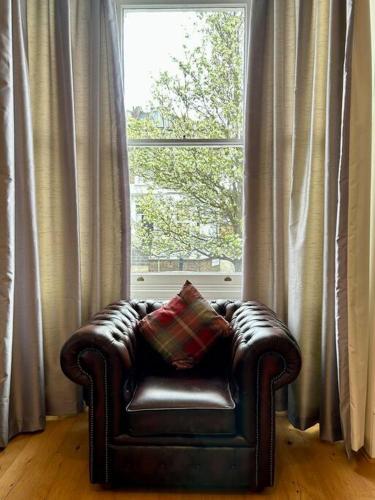 skórzane krzesło siedzące przed oknem w obiekcie 1 bedroom apartment in Shepherds Bush, London w Londynie