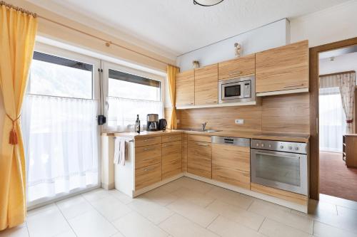 a kitchen with wooden cabinets and a large window at Pension Glockenstuhl in Finkenberg