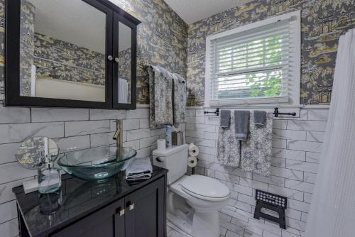 Un baño con lavabo, inodoro y ventana. en Bama Bungalow, en Tuscaloosa