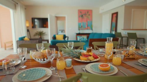 a table with plates of food and glasses of orange juice at Villa Maorie 5 chambres avec piscine privée in Le François