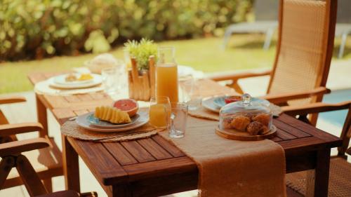 a wooden table with plates of food and orange juice at Villa Maorie 5 chambres avec piscine privée in Le François