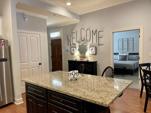 a kitchen with a island with a welcome sign on the wall at BamaNati in Tuscaloosa