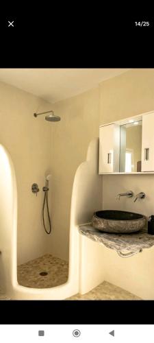 een badkamer met een bad, een wastafel en een douche bij Mikro Kastro in Amorgós