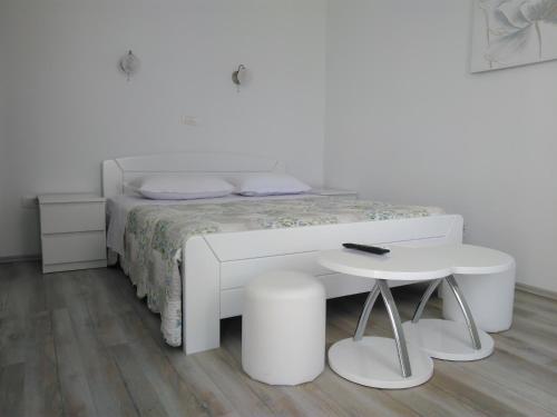 ein weißes Schlafzimmer mit einem weißen Bett und einem Tisch in der Unterkunft Lemon house in Vis
