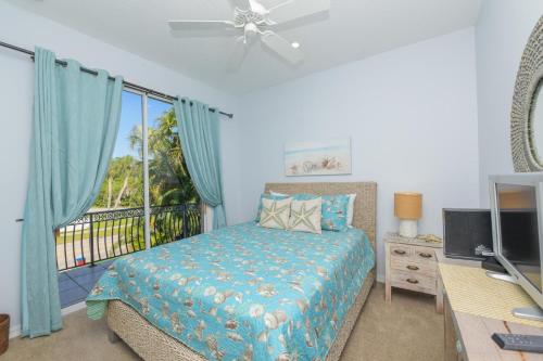 a bedroom with a bed and a balcony with a television at Tarpon Villa in Siesta Key