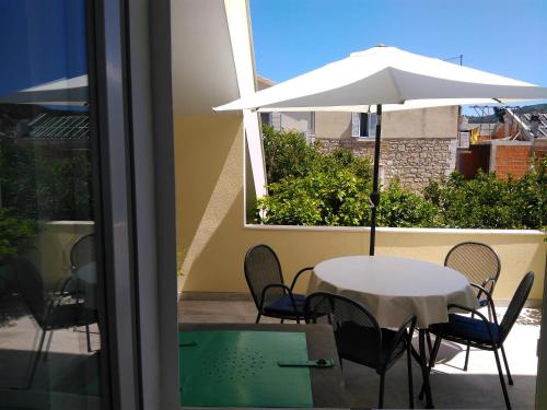 einen Tisch und Stühle mit Sonnenschirm auf dem Balkon in der Unterkunft Lemon house in Vis
