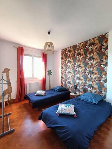 2 camas en una habitación con sábanas azules en Les jardins Ducarouge 1, en Digoin