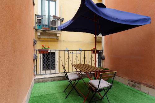 a table and chairs and an umbrella on a balcony at Casta Diva Holiday Rooms in Catania