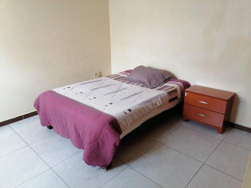 1 cama con manta morada y mesita de noche en Casa Cerca estadio Akron y plaza del sol, en Guadalajara