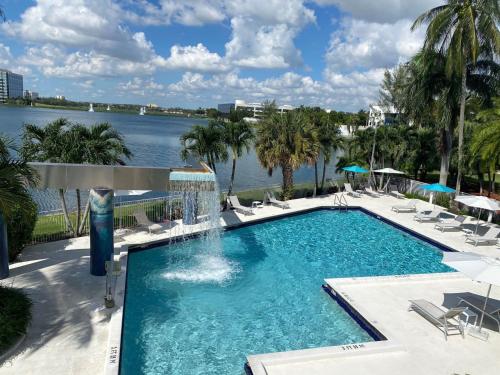 a large swimming pool with chairs and a body of water at Pullman Miami Airport in Miami