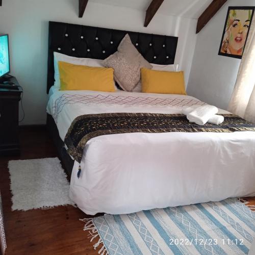 een slaapkamer met een groot wit bed met gele kussens bij Zagorski’s Bed and breakfast in Bloubergstrand