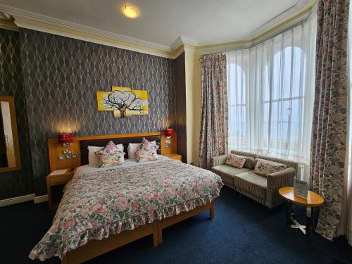 a bedroom with a bed and a couch and a window at Iris Hotel Llandudno in Llandudno