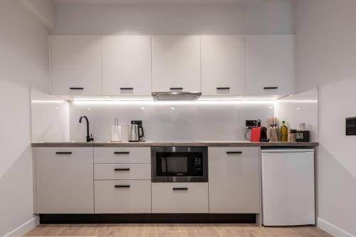 eine Küche mit weißen Schränken und einer Mikrowelle in der Unterkunft A&N Athens Luxury Apartments - Ermou in Athen