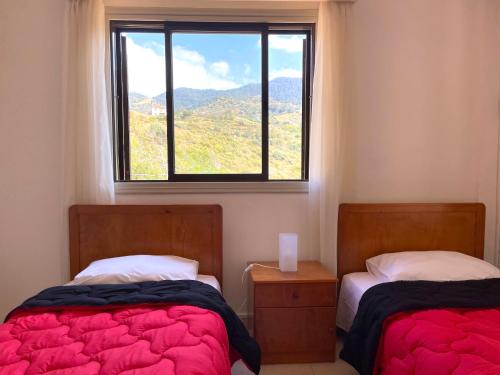 two beds in a room with a window at Nysa8 in Paphos City