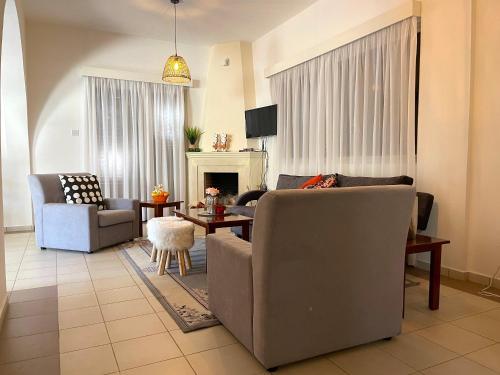 a living room with two chairs and a couch and a table at Nysa8 in Paphos City
