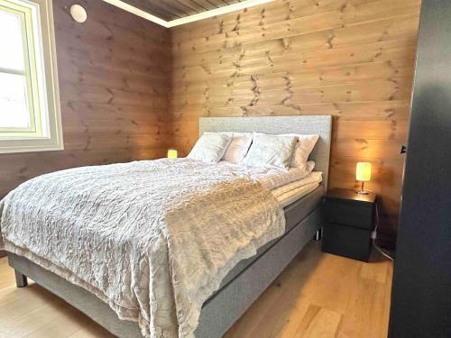 a bedroom with a bed and a wooden wall at Lovise Mountain Apartment in Stranda