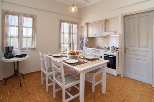 a kitchen with a white table and chairs and a counter at Magnolia Apartments in Fiskardho
