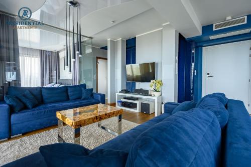 a living room with blue couches and a table at Prezydencki Apartamenty z widokiem na morze in Jarosławiec