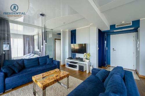 a living room with a blue couch and a table at Prezydencki Apartamenty z widokiem na morze in Jarosławiec