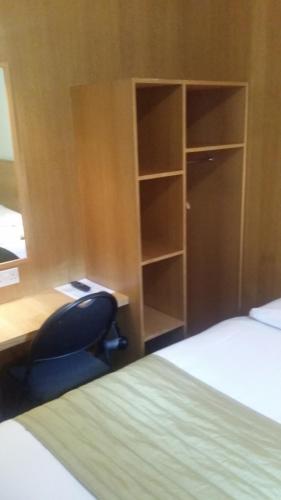 a bedroom with a desk and a chair next to a bed at Arriva Hotel in London