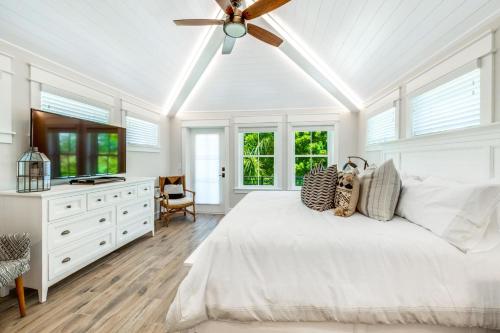 um quarto branco com uma cama e uma ventoinha de tecto em The Shore House em Bailey Hall