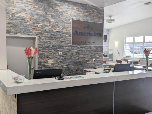 an office with a reception desk with a brick wall at AmericInn by Wyndham Green Bay Near Stadium in Green Bay