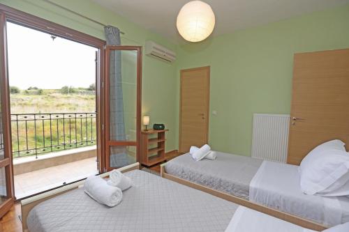 two beds in a room with a balcony at Mesaria House Syros in Ermoupoli