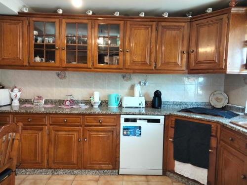 cocina con armarios de madera y lavavajillas blanco en Casa da Emilia do Gerês en Outeiro