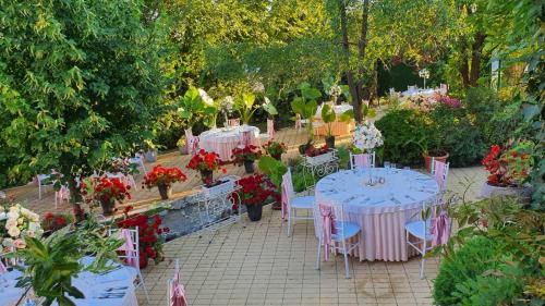 Kesten Futog في Futog: مجموعة طاولات وكراسي في حديقة بها ورد
