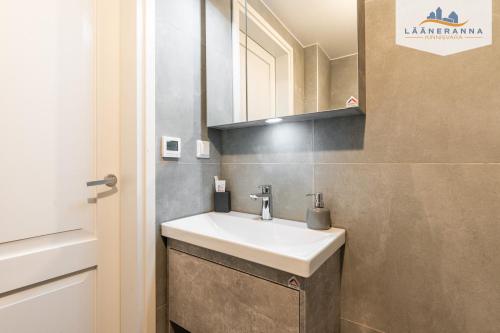 La salle de bains est pourvue d'un lavabo blanc et d'un miroir. dans l'établissement Promenaadi apartament, à Haapsalu