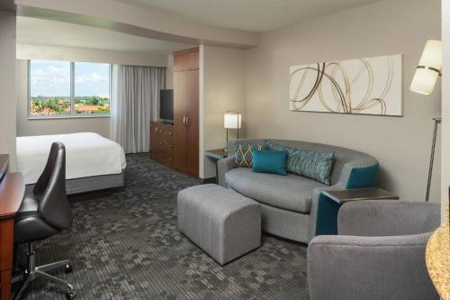 a hotel room with a bed and a living room at Courtyard by Marriott Miami Airport in Miami