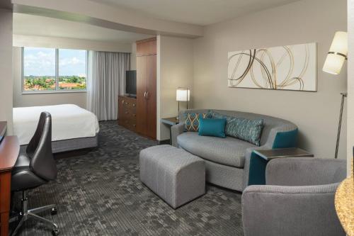 Habitación de hotel con cama y sala de estar. en Courtyard by Marriott Miami Airport en Miami