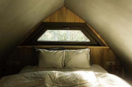 a bed with two pillows and a window in a tent at Jungle SPA bungalows in Žocenes Ciems