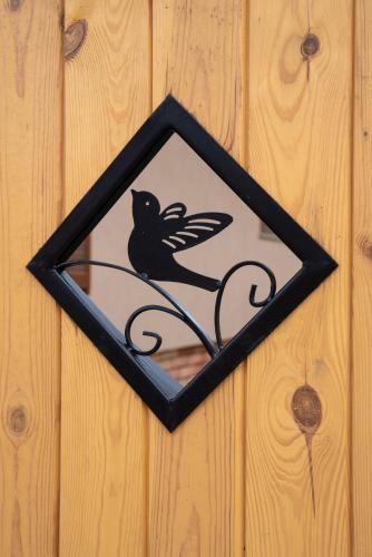 a black and white bird sign on a wooden wall at Benige vendégház in Demjén