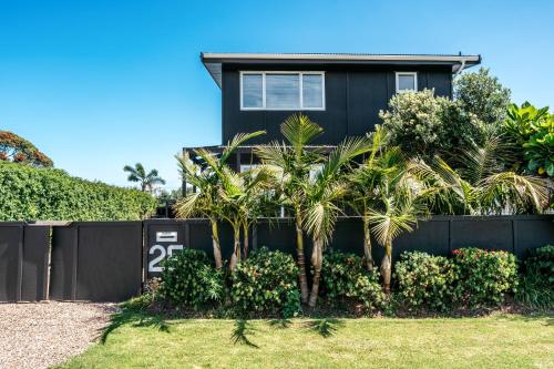 a house with palm trees in front of a fence at Oneroa Coastal Classic - Coast & Country in Oneroa